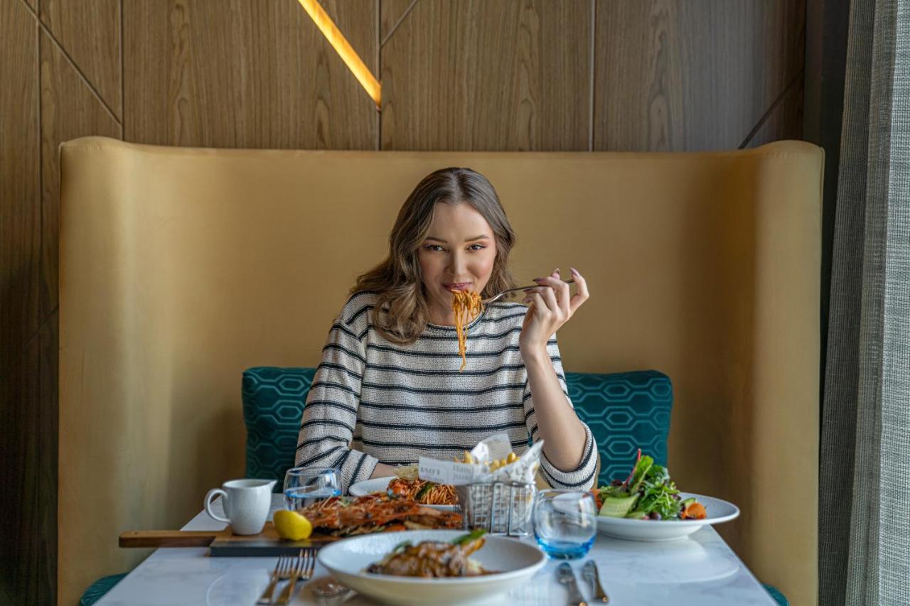 Pullman Sharjah Hotel Kültér fotó A woman eating at a restaurant